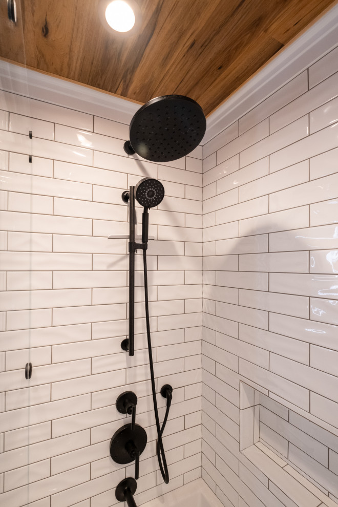 Idées déco pour une salle de bain principale contemporaine en bois brun de taille moyenne avec un placard à porte shaker, une baignoire en alcôve, un combiné douche/baignoire, un carrelage blanc, un carrelage métro, un sol en carrelage de porcelaine, une vasque, un plan de toilette en surface solide, un sol gris, une cabine de douche à porte coulissante, un plan de toilette noir, des toilettes cachées, meuble double vasque, meuble-lavabo encastré et un plafond en bois.