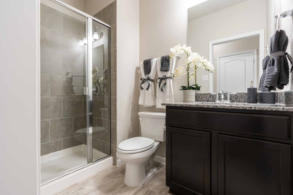 Inspiration for a medium sized classic family bathroom in Austin with recessed-panel cabinets, dark wood cabinets, an alcove bath, a shower/bath combination, a two-piece toilet, beige tiles, ceramic tiles, beige walls, ceramic flooring, a submerged sink, granite worktops, beige floors, a shower curtain, grey worktops, a single sink and a built in vanity unit.