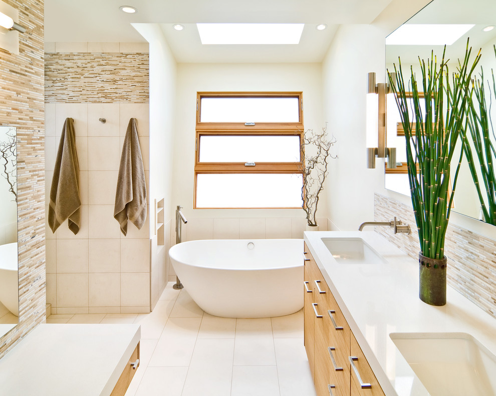 Cette image montre une salle de bain principale design en bois clair avec un lavabo encastré, un placard à porte plane, une baignoire indépendante, un carrelage marron et des carreaux en allumettes.