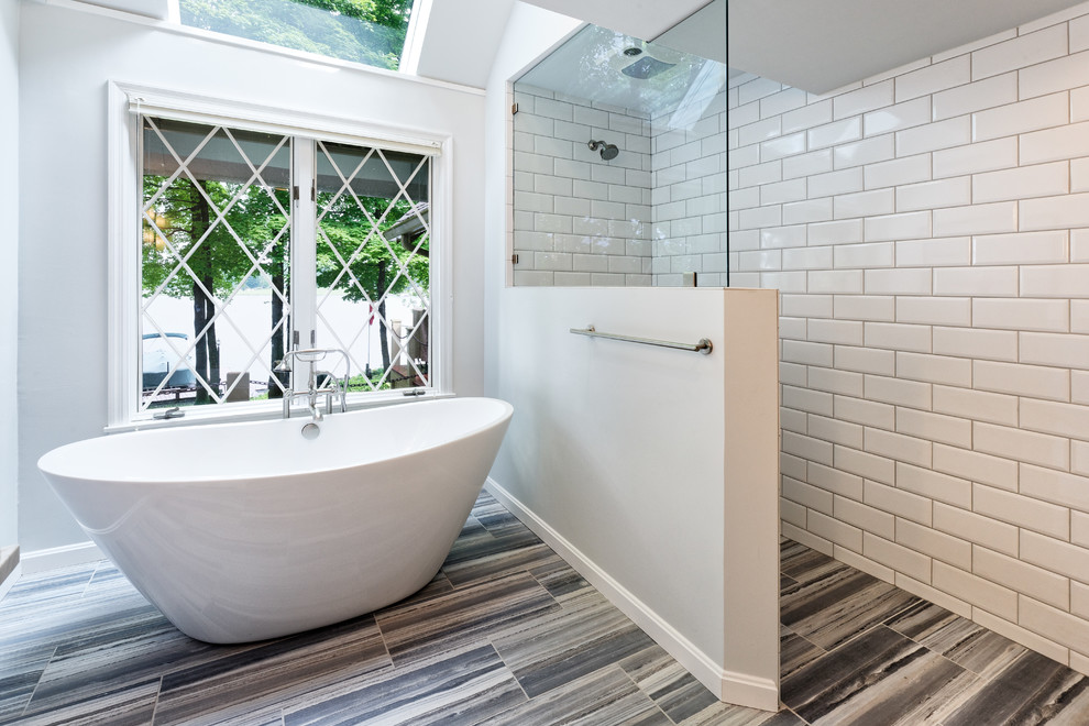 На фото: ванная комната с отдельно стоящей ванной, душем без бортиков, белой плиткой, керамической плиткой, белыми стенами, полом из керамогранита, синим полом и открытым душем с