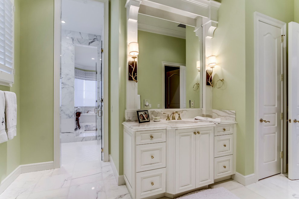 Large traditional ensuite bathroom in Miami with a built-in sink, raised-panel cabinets, white cabinets, marble worktops, a double shower, a two-piece toilet, white tiles, stone slabs, green walls and marble flooring.
