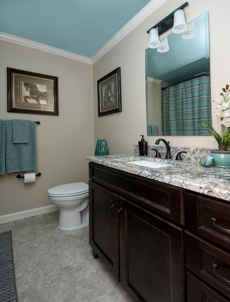 Inspiration for a medium sized traditional shower room bathroom in Louisville with recessed-panel cabinets, black cabinets, an alcove bath, a shower/bath combination, a two-piece toilet, beige tiles, ceramic tiles, beige walls, ceramic flooring, a submerged sink, granite worktops, grey floors, a shower curtain and grey worktops.