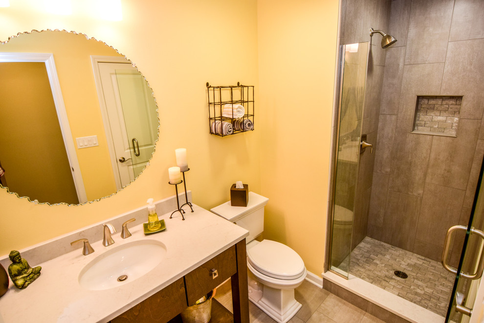 Стильный дизайн: маленькая ванная комната в стиле неоклассика (современная классика) с плоскими фасадами, фасадами цвета дерева среднего тона, душем в нише, раздельным унитазом, серой плиткой, керамогранитной плиткой, желтыми стенами, полом из керамогранита, душевой кабиной, врезной раковиной и столешницей из искусственного камня для на участке и в саду - последний тренд