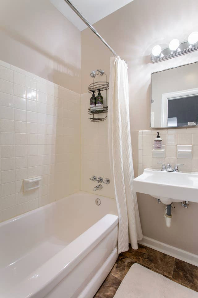 Aménagement d'une salle de bain classique de taille moyenne avec une baignoire en alcôve, un combiné douche/baignoire, un carrelage blanc, des carreaux de porcelaine, un mur beige, un sol en linoléum, un lavabo suspendu, un sol beige, aucune cabine et meuble simple vasque.