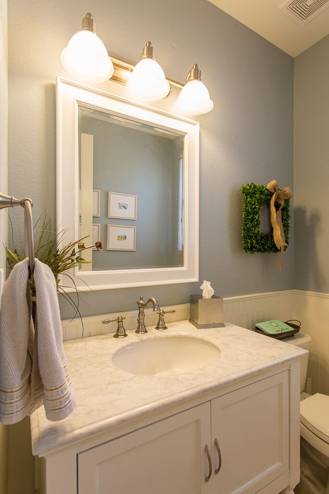 Foto på ett litet vintage badrum med dusch, med släta luckor, vita skåp, en toalettstol med separat cisternkåpa, vit kakel, blå väggar, klinkergolv i keramik, ett undermonterad handfat, marmorbänkskiva och beiget golv