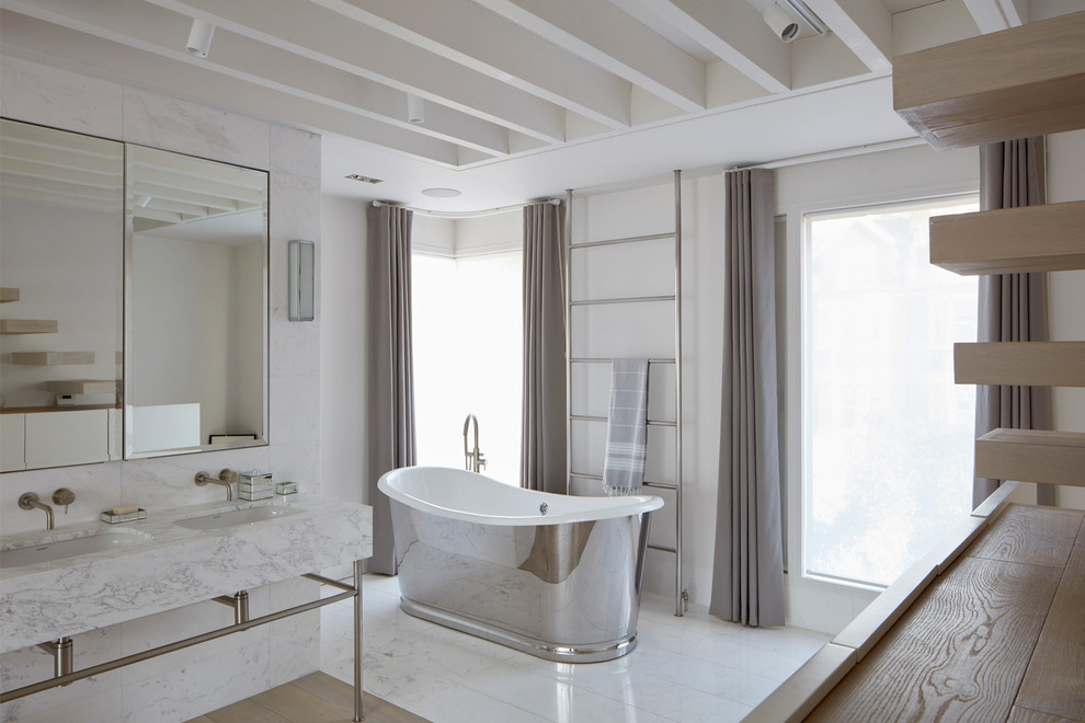 Réalisation d'une salle de bain tradition avec une baignoire indépendante, un mur blanc et un lavabo encastré.