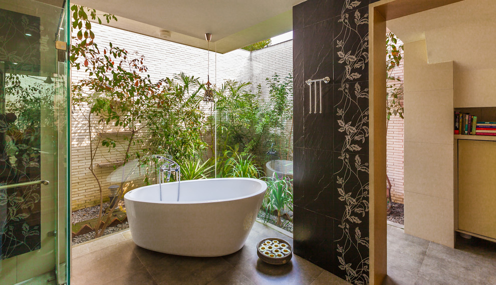Foto på ett funkis badrum, med ett fristående badkar, en hörndusch och svart kakel