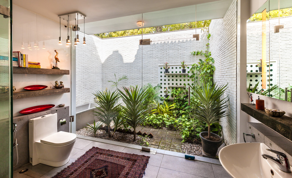 デリーにあるエクレクティックスタイルのおしゃれな浴室 (壁付け型シンク、コーナー設置型シャワー、一体型トイレ	、白いタイル) の写真