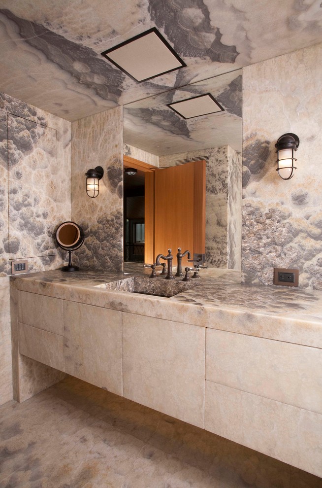 Immagine di una stanza da bagno design con lavabo integrato, ante lisce e lastra di pietra