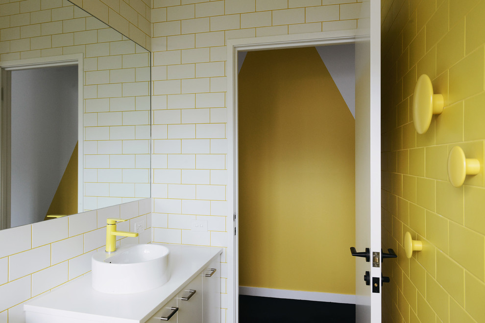 Photo of a bathroom in Melbourne with white cabinets, yellow tiles, ceramic tiles, yellow walls and a vessel sink.