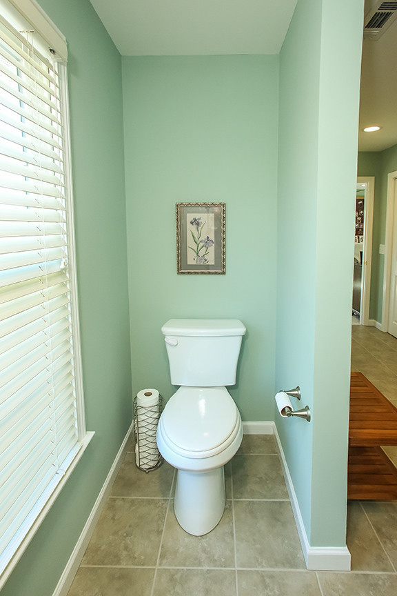 Cette image montre un WC et toilettes traditionnel de taille moyenne avec un placard avec porte à panneau surélevé, des portes de placard blanches, un mur vert, un sol en carrelage de céramique et un lavabo encastré.