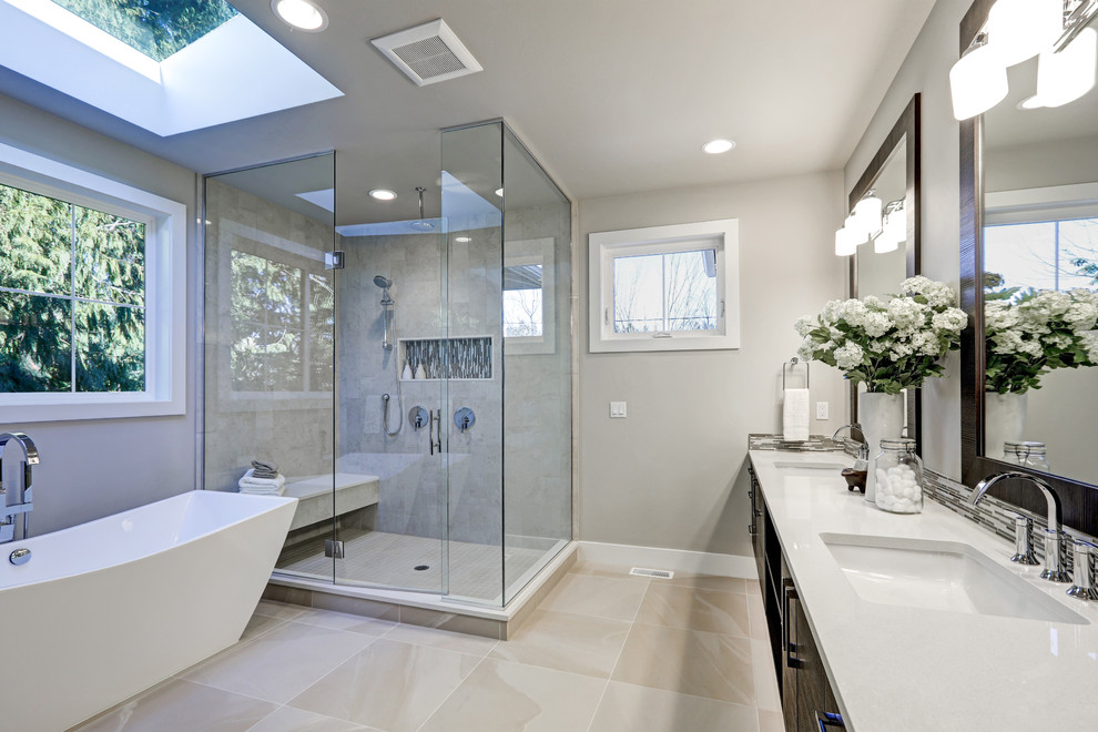 Design ideas for a large modern ensuite bathroom in Jacksonville with flat-panel cabinets, dark wood cabinets, a freestanding bath, a corner shower, grey tiles, porcelain tiles, grey walls, a submerged sink, quartz worktops, beige floors, a hinged door, white worktops, mosaic tile flooring, double sinks and a floating vanity unit.