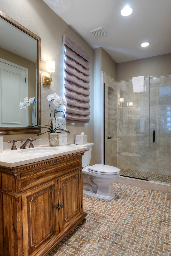 На фото: ванная комната в классическом стиле с врезной раковиной, фасадами цвета дерева среднего тона, душем в нише, раздельным унитазом, бежевой плиткой, каменной плиткой, бежевыми стенами и фасадами с утопленной филенкой
