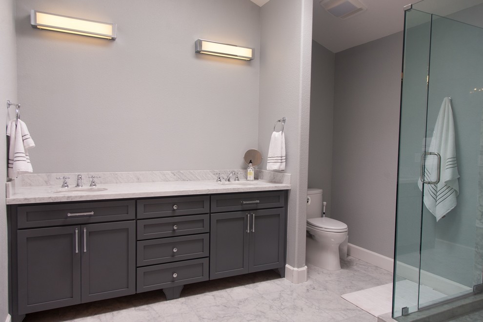 Foto de cuarto de baño contemporáneo grande con lavabo bajoencimera, armarios con paneles empotrados, puertas de armario grises, ducha esquinera, sanitario de una pieza, baldosas y/o azulejos grises, paredes grises y aseo y ducha