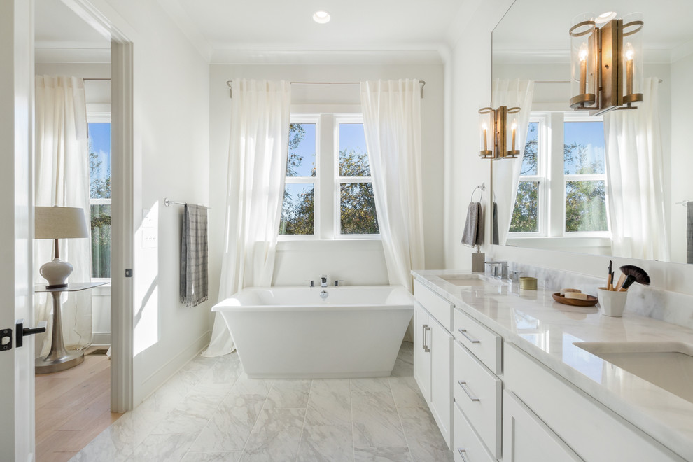 Imagen de cuarto de baño clásico renovado con armarios estilo shaker, puertas de armario blancas, bañera exenta, paredes blancas, lavabo bajoencimera, suelo blanco y encimeras blancas