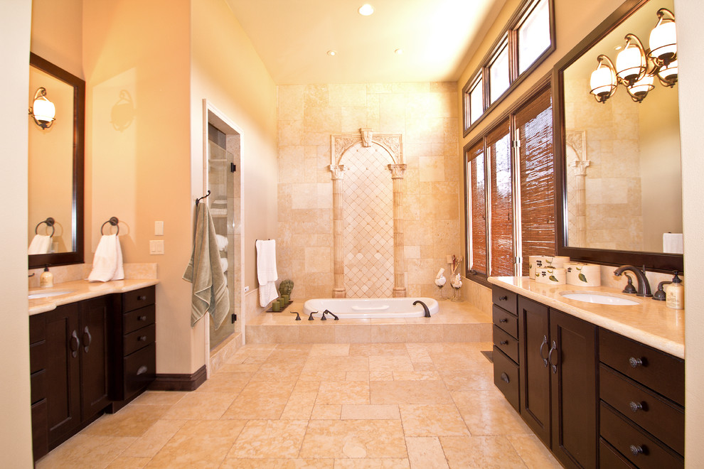 This is an example of a traditional ensuite bathroom in Other with a built-in bath, a submerged sink, recessed-panel cabinets, dark wood cabinets, marble worktops, an alcove shower, beige tiles, stone tiles, beige walls and travertine flooring.