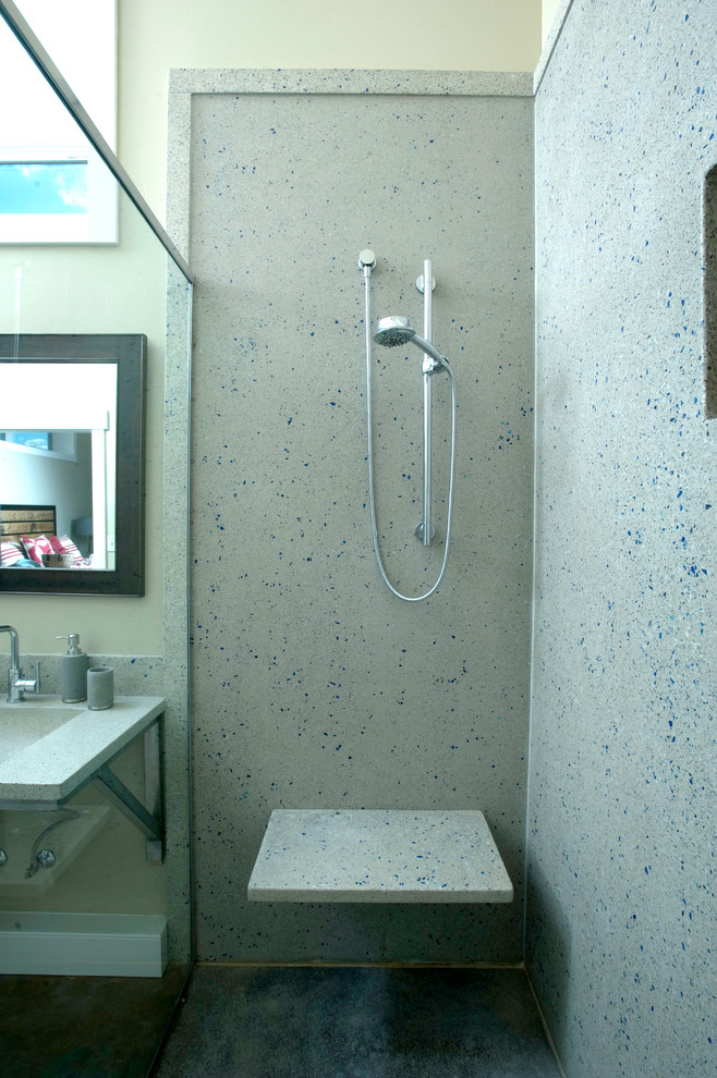 Example of a large urban master gray tile and cement tile concrete floor double shower design in Other with medium tone wood cabinets, a one-piece toilet, gray walls, an integrated sink and recycled glass countertops