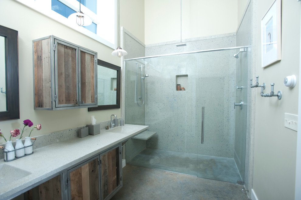 Idéer för att renovera ett stort industriellt en-suite badrum, med skåp i mellenmörkt trä, en dubbeldusch, en toalettstol med hel cisternkåpa, grå kakel, cementkakel, grå väggar, betonggolv, ett integrerad handfat och bänkskiva i återvunnet glas