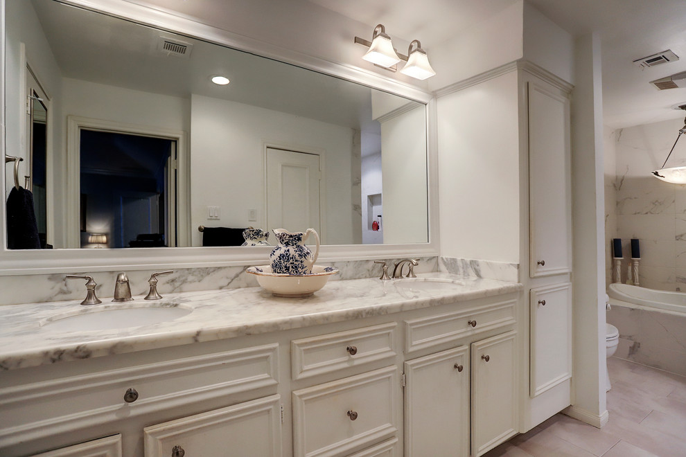 Example of a transitional master drop-in bathtub design in Houston with marble countertops and white countertops