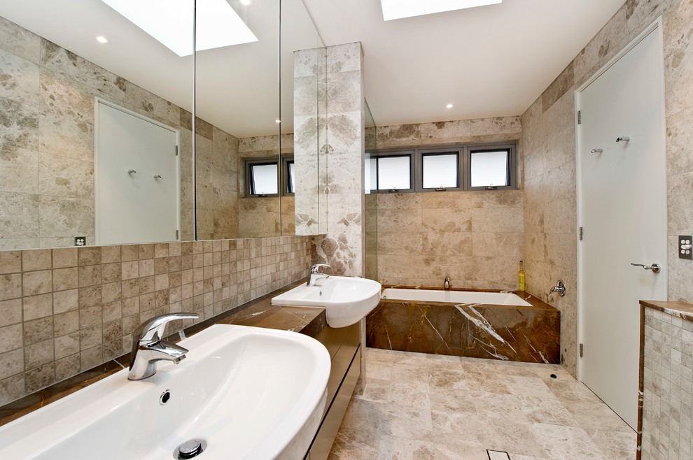 Inredning av ett modernt en-suite badrum, med släta luckor, skåp i mörkt trä och ett undermonterat badkar