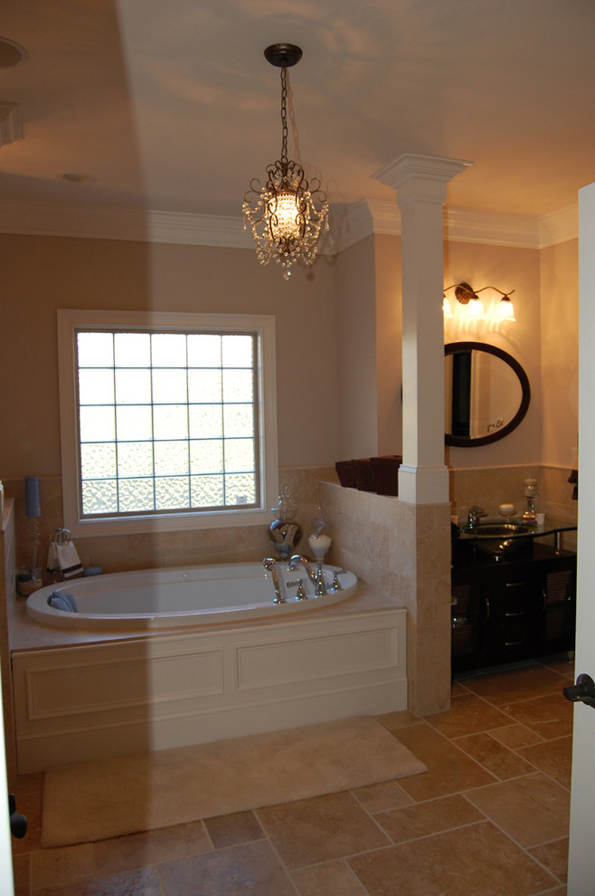 Idee per una grande stanza da bagno padronale classica con vasca da incasso, piastrelle beige, piastrelle di pietra calcarea, pareti beige, pavimento in pietra calcarea, lavabo da incasso e top in vetro