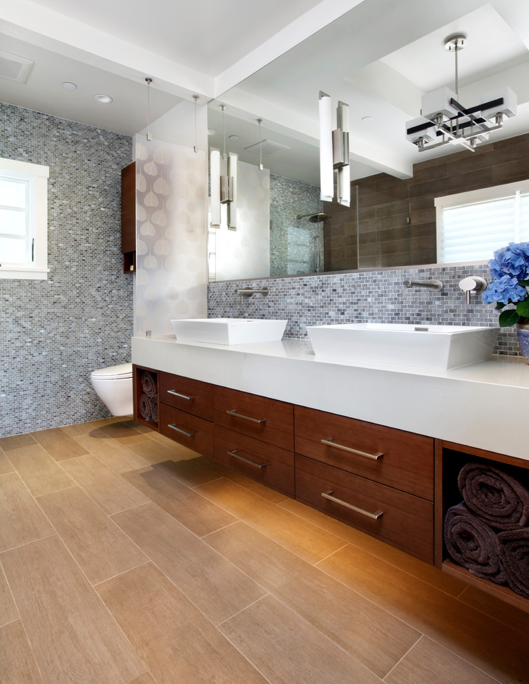 Esempio di una stanza da bagno contemporanea con lavabo a bacinella, ante lisce, ante in legno bruno, WC sospeso, piastrelle grigie e piastrelle a mosaico