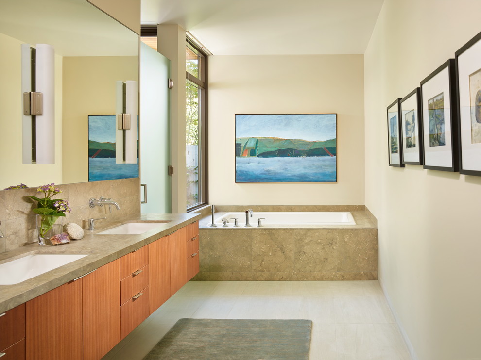 Свежая идея для дизайна: ванная комната в современном стиле с плоскими фасадами, фасадами цвета дерева среднего тона, накладной ванной, бежевой плиткой, бежевыми стенами, врезной раковиной и плиткой из известняка - отличное фото интерьера