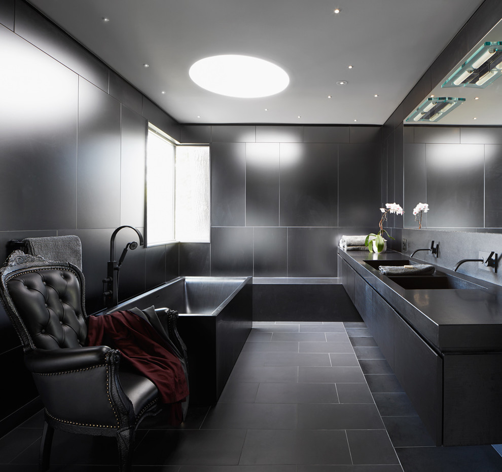 トロントにあるコンテンポラリースタイルのおしゃれなマスターバスルーム (黒いタイル、一体型シンク、フラットパネル扉のキャビネット、黒いキャビネット、御影石の洗面台、置き型浴槽) の写真