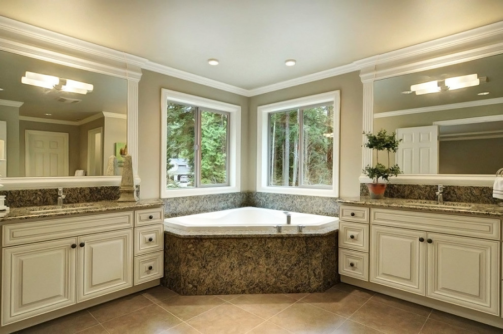 Immagine di una stanza da bagno padronale classica con ante con bugna sagomata, ante bianche, vasca idromassaggio, pareti beige, pavimento in gres porcellanato, lavabo sottopiano e top in granito