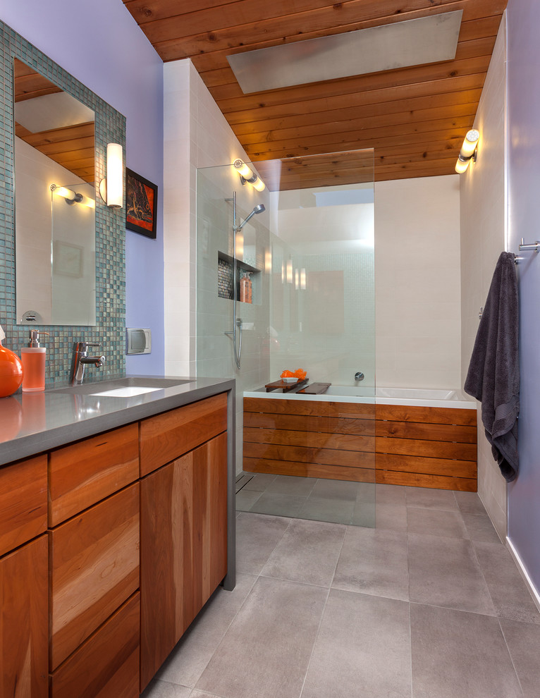 Aménagement d'une salle de bain principale rétro en bois brun de taille moyenne avec un placard à porte plane, une baignoire en alcôve, une douche ouverte, WC suspendus, un carrelage gris, des carreaux de porcelaine, un mur violet, un sol en carrelage de porcelaine, un lavabo encastré et un plan de toilette en quartz modifié.