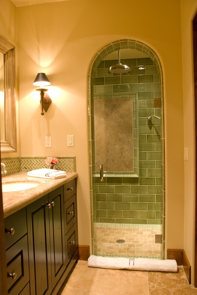 Example of a mid-sized transitional 3/4 green tile and porcelain tile travertine floor alcove shower design in Phoenix with raised-panel cabinets, dark wood cabinets, a one-piece toilet, beige walls, an undermount sink, marble countertops and a hinged shower door
