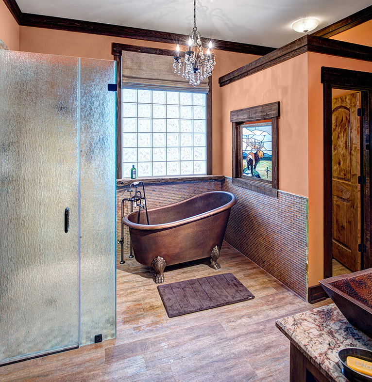 Inredning av ett badrum, med granitbänkskiva, ett badkar med tassar, en öppen dusch, mosaik, orange väggar och ljust trägolv