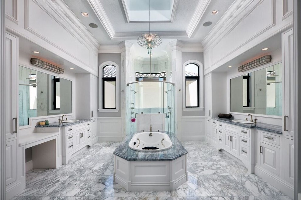 Источник вдохновения для домашнего уюта: огромная главная ванная комната в классическом стиле с фасадами с выступающей филенкой, белыми фасадами, накладной ванной, душем в нише, серой плиткой, каменной плиткой, серыми стенами, накладной раковиной, душем с распашными дверями, мраморным полом, мраморной столешницей и серым полом
