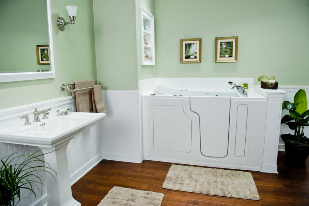 Свежая идея для дизайна: большая главная ванная комната в стиле неоклассика (современная классика) с угловой ванной, зелеными стенами, темным паркетным полом, раковиной с пьедесталом и коричневым полом - отличное фото интерьера