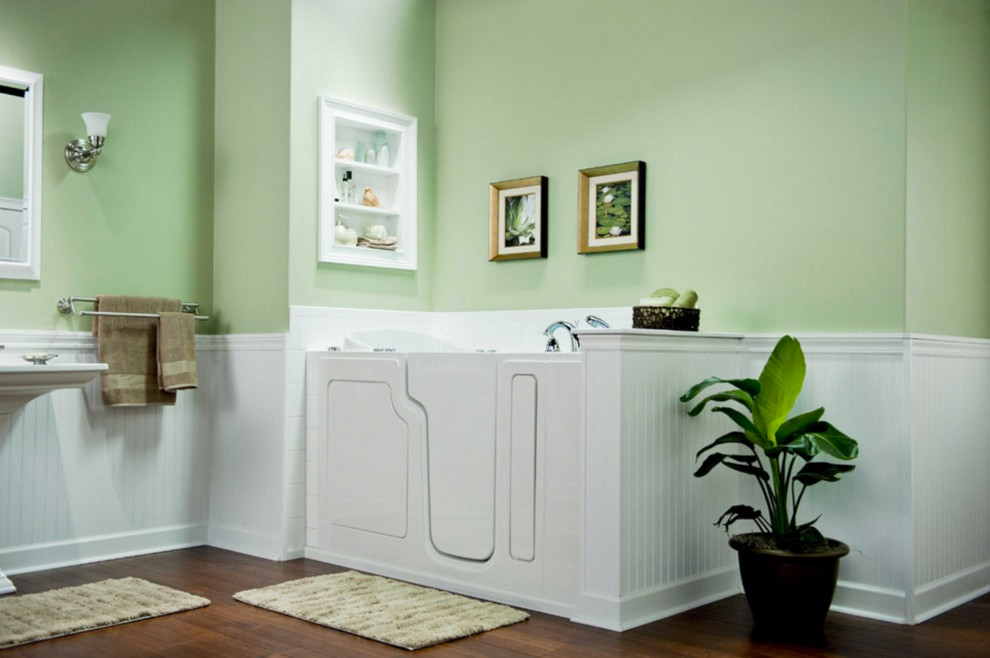 На фото: большая главная ванная комната в стиле неоклассика (современная классика) с угловой ванной, зелеными стенами, темным паркетным полом, раковиной с пьедесталом и коричневым полом с