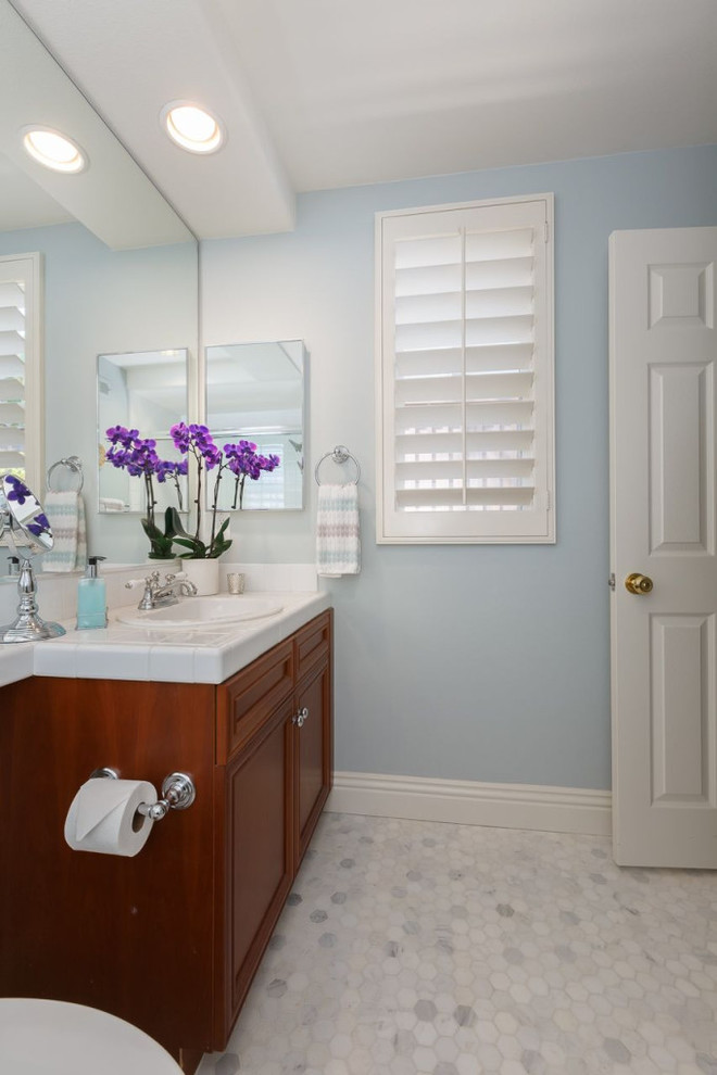 Пример оригинального дизайна: ванная комната в классическом стиле с накладной раковиной, фасадами с утопленной филенкой, фасадами цвета дерева среднего тона, столешницей из плитки, унитазом-моноблоком, белой плиткой, керамической плиткой, синими стенами, полом из мозаичной плитки и душевой кабиной