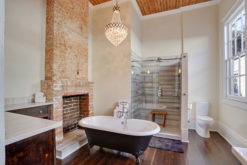 Bathroom - mid-sized rustic master gray tile and white tile medium tone wood floor and brown floor bathroom idea in New Orleans with dark wood cabinets, flat-panel cabinets, a one-piece toilet, beige walls, quartz countertops, a hinged shower door and white countertops