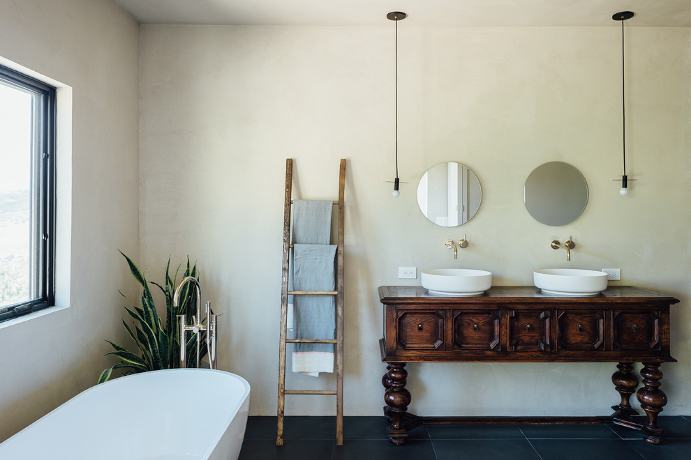 Exempel på ett mellanstort eklektiskt en-suite badrum, med ett fristående badkar, en öppen dusch, en toalettstol med hel cisternkåpa, rosa kakel, cementkakel, vita väggar, klinkergolv i keramik, ett piedestal handfat och svart golv