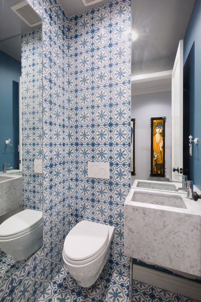Cette image montre une petite salle de bain bohème avec WC suspendus, un carrelage bleu, un carrelage blanc, des carreaux de béton, un mur multicolore, carreaux de ciment au sol, un lavabo intégré et un sol multicolore.