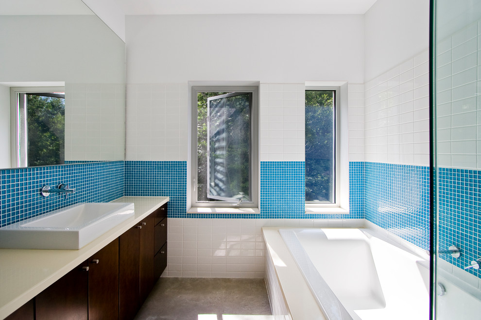 Foto di una stanza da bagno contemporanea con ante lisce, ante in legno bruno, piastrelle blu, lavabo a bacinella, vasca da incasso e piastrelle a mosaico