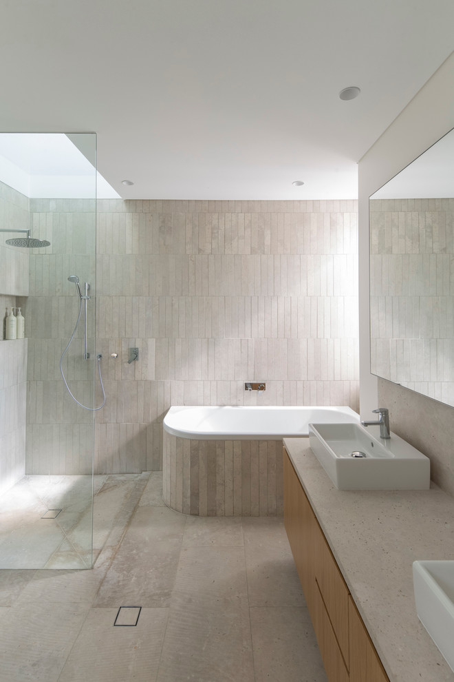 Diseño de cuarto de baño principal actual con lavabo sobreencimera, armarios con paneles lisos, puertas de armario de madera clara, bañera encastrada, ducha esquinera y baldosas y/o azulejos grises
