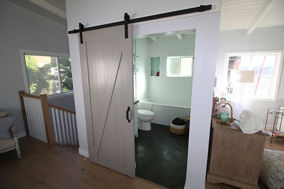 Inredning av ett lantligt mellanstort badrum, med ett badkar i en alkov, en dusch/badkar-kombination, en toalettstol med separat cisternkåpa, vit kakel, vita väggar, klinkergolv i porslin och svart golv