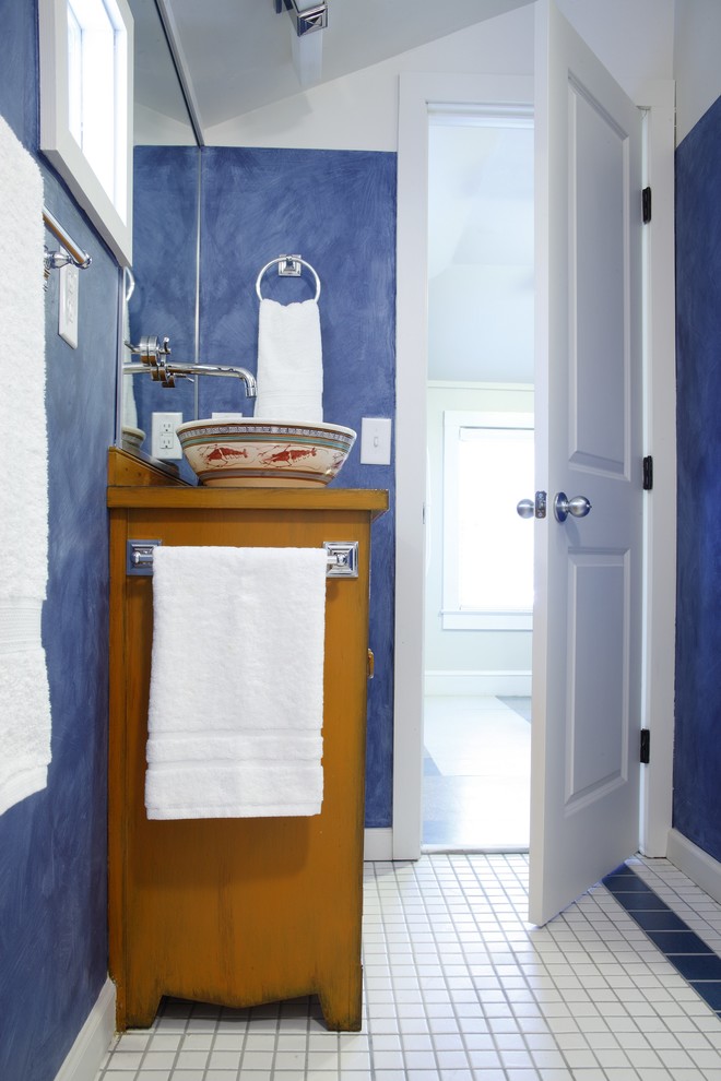Eklektisk inredning av ett badrum, med ett fristående handfat, möbel-liknande, träbänkskiva, en dusch i en alkov, en toalettstol med separat cisternkåpa, flerfärgad kakel, keramikplattor och gula skåp