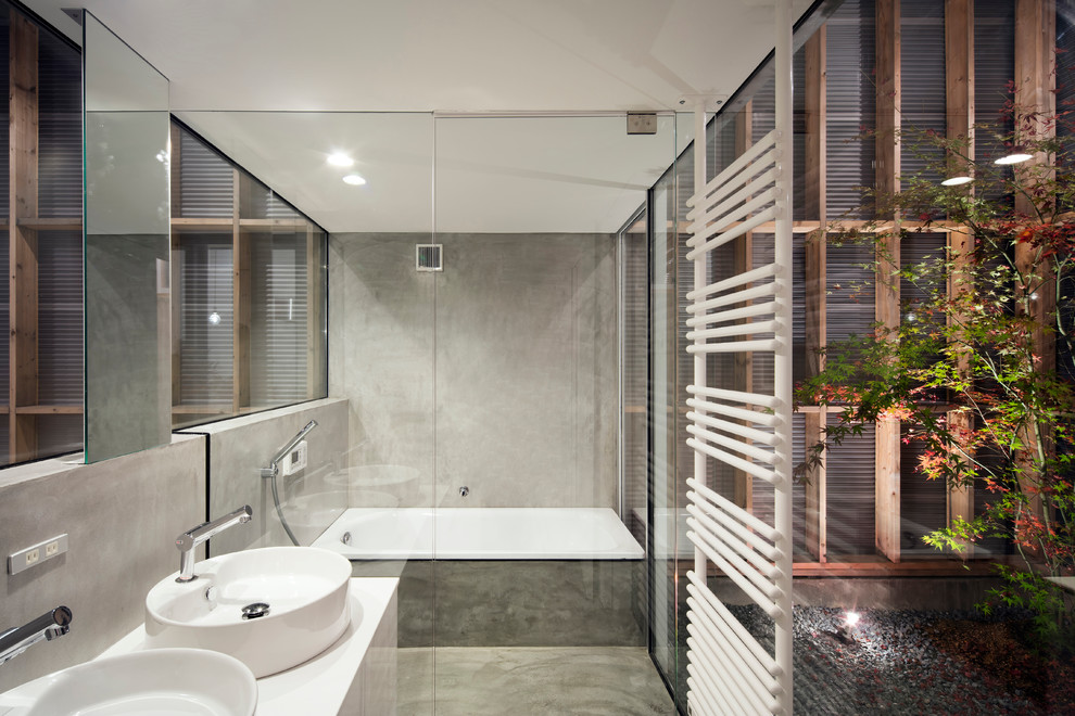 京都にあるインダストリアルスタイルのおしゃれな浴室 (オープン型シャワー、グレーの壁、コンクリートの床、ベッセル式洗面器、開き戸のシャワー、白いキャビネット、白い洗面カウンター、洗面台2つ、造り付け洗面台、フラットパネル扉のキャビネット) の写真
