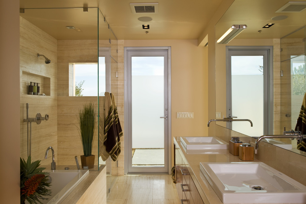 Foto de cuarto de baño principal moderno grande con lavabo sobreencimera, armarios con paneles lisos, puertas de armario de madera oscura, ducha esquinera, paredes beige y suelo de travertino