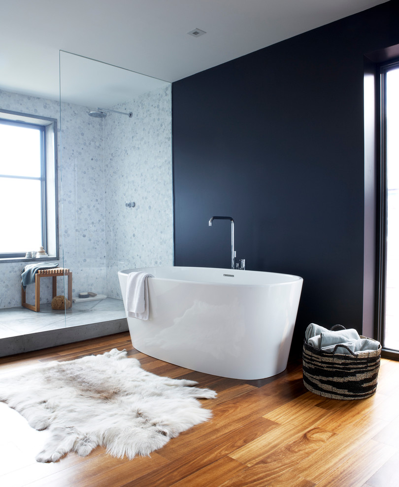 Réalisation d'une salle de bain design avec une baignoire indépendante, une douche ouverte, un carrelage blanc, un mur noir, un sol en bois brun et aucune cabine.