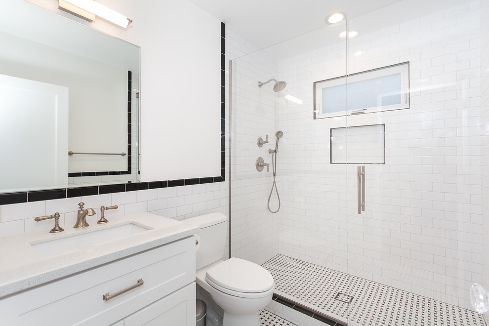 ロサンゼルスにあるお手頃価格の中くらいなコンテンポラリースタイルのおしゃれなバスルーム (浴槽なし) (インセット扉のキャビネット、白いキャビネット、アルコーブ型シャワー、一体型トイレ	、白いタイル、サブウェイタイル、白い壁、セラミックタイルの床、オーバーカウンターシンク、御影石の洗面台、白い床、引戸のシャワー、白い洗面カウンター) の写真