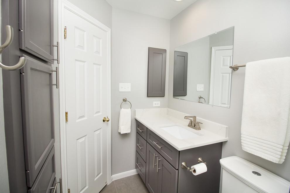 Exemple d'une petite salle d'eau chic avec un placard à porte shaker, des portes de placard grises, une baignoire en alcôve, un combiné douche/baignoire, un carrelage blanc, des carreaux de porcelaine, un mur gris, un sol en carrelage de porcelaine, un lavabo encastré, un plan de toilette en quartz modifié, un sol gris et une cabine de douche à porte coulissante.