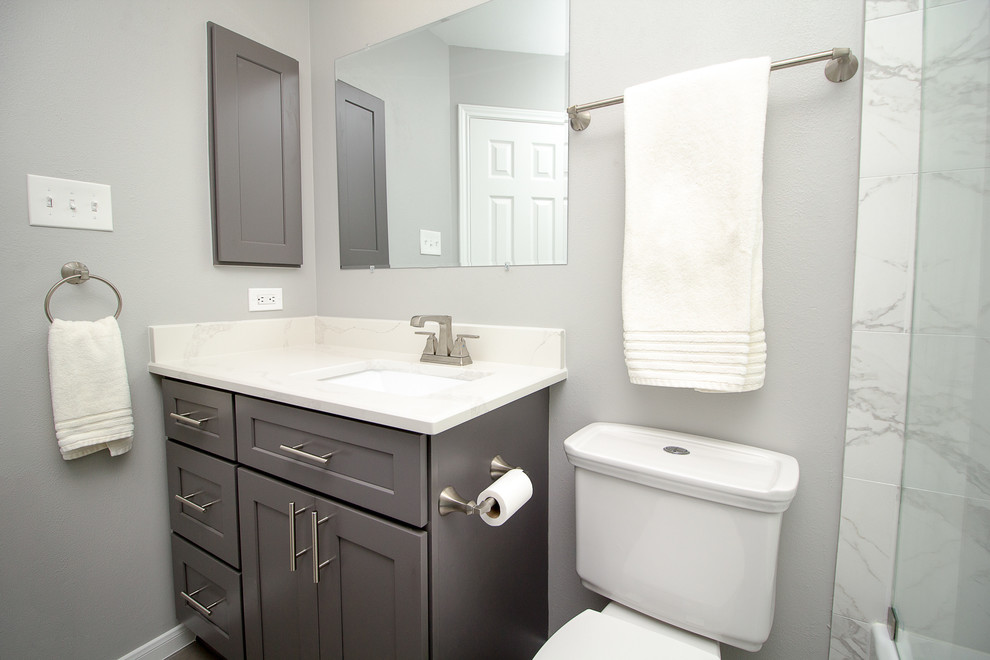 Idée de décoration pour une petite salle d'eau tradition avec un placard à porte shaker, des portes de placard grises, une baignoire en alcôve, un combiné douche/baignoire, un carrelage blanc, des carreaux de porcelaine, un mur gris, un sol en carrelage de porcelaine, un lavabo encastré, un plan de toilette en quartz modifié, un sol gris et une cabine de douche à porte coulissante.