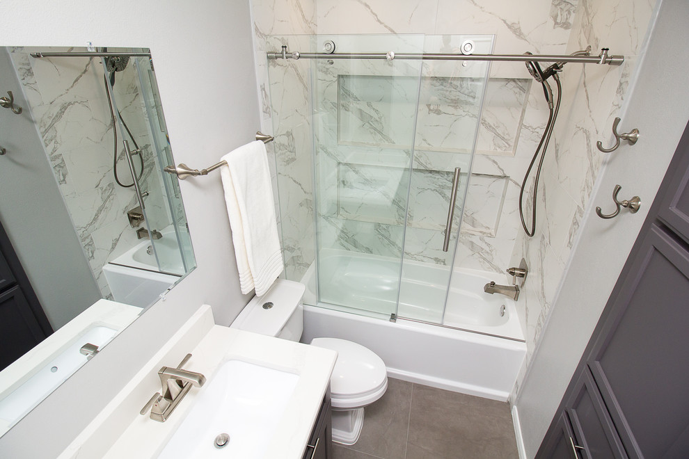 На фото: маленькая ванная комната в стиле неоклассика (современная классика) с фасадами в стиле шейкер, серыми фасадами, ванной в нише, душем над ванной, белой плиткой, керамогранитной плиткой, серыми стенами, полом из керамогранита, душевой кабиной, врезной раковиной, столешницей из искусственного кварца, серым полом и душем с раздвижными дверями для на участке и в саду с